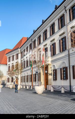 Budapest, Ungarn - Nov 6, 2019: Straße mit Kopfsteinpflaster im Burgviertel mit dem Bau des Gerichtshof Theater von Buda. Das historische Zentrum von Budapest. Die Menschen gehen auf die Straße. Stockfoto