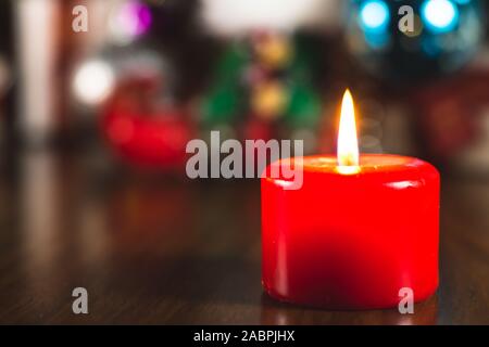 Kerzen brennen mit Flamme vor einem Weihnachtsbaum mit Dekorationen und Verzierungen. Stockfoto
