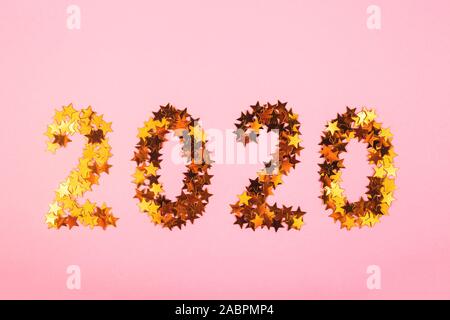 2020 Neue Jahr mit Zahlen von golden leuchtenden Sternen aufgereiht auf einem hellen Rosa Hintergrund. Winter Ferien und Weihnachten Konzept. Ansicht von oben, flach. Stockfoto