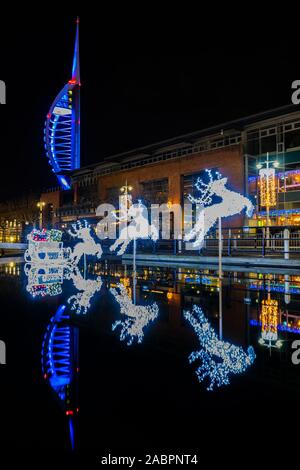 Die Spinnaker Tower in Portsmouth Gunwharf Quays mit Weihnachten Rentier Lichter auf dem Wasser in der Nacht spiegeln Stockfoto