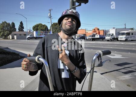 Älterer lateinamerikanischer mexikanischer Teenager-Junge mit Helm, der Handsignale von seinem Fahrrad auf der Straße in ganz schwarz macht und stolz auf sein Aussehen ist Stockfoto