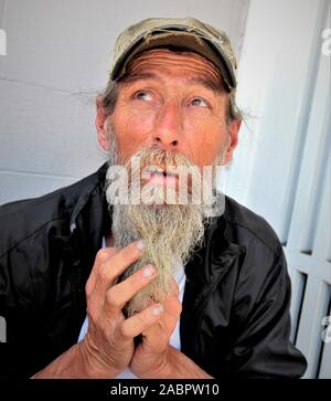 Mehr als 60 Jahre alter Mann, der der Öffentlichkeit seinen Bart zeigt, während er auf den Straßen von Los Angeles lebt und nicht als obdachlos gilt und in ein Zimmer zurückgezogen wird Stockfoto