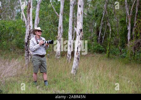 Männliche Fotograf hält Kamera und Objektiv während erfassen Bilder in Buschland in Australien Stockfoto