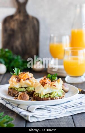 Sandwich mit Avocado und Orsini Ei auf Getreide Brot mit geröstetem Speck zum Frühstück. Leichte und gesunde Frühstück von einfachen Produkten. Comforta Stockfoto