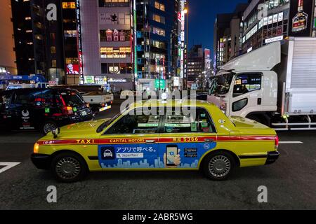 Ein japanisches Taxi (gelbes Taxi) in einer Straße mit anderem Verkehr in Shinjuku, Tokio, Japan. Stockfoto