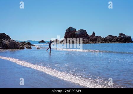 Fischer casting seinen Stab zwischen den Felsen am Strand Stockfoto