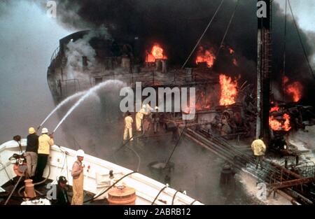 (Jan. 8) - - Feuerwehrmänner halten das Wasser fließt auf einer brennenden Tanker als Arbeiter an Bord arbeiten fieberhaft daran, die Schieber zu schließen, um so eine Brandausbreitung zu verhindern. Stockfoto