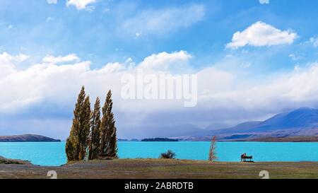 Ein paar sitzen auf einer Bank am See Tekapo in Neuseeland und bewundern Sie die bunten blauen Wasser Stockfoto