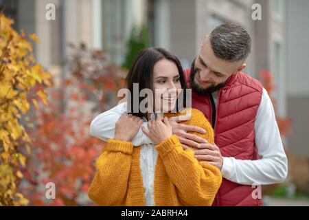 Liebe und Fürsorge. Positive junger Mann lächelnd, während seine Freundin umarmen Stockfoto