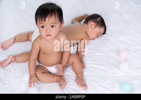 2 Babys auf ein Bett, ein Wohnzimmer, 1 Schlaf Stockfoto