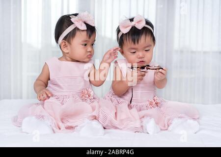 2 Babys in rosa Kleid auf einem Bett. Stockfoto