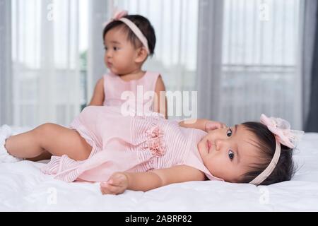 2 Babys in rosa Kleid auf einem Bett. Stockfoto