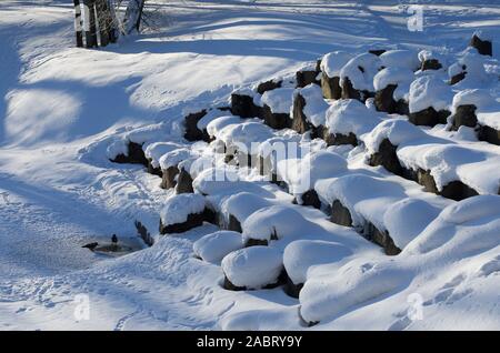 Winterlandschaft mit Felsbrocken bedeckt mit Schnee auf dem gefrorenen Granit Kaskade von einem kleinen Wasserfall Stockfoto