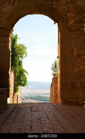 Einen Bogen und ferne Landschaft gesehen, das in der ummauerten historische Architektur der UNESCO Renaissance hilltop Stadt Pienza Toskana Italien Europa Stockfoto