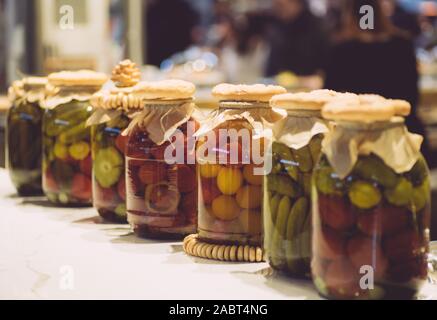 Eingelegte Gurken und Tomaten im Glas auf dem Tisch. Pickles aus Gemüse. Vegetarisches Essen. Stockfoto