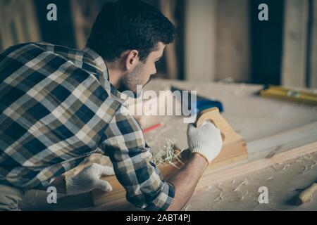 Oben über hohen Winkel anzeigen Foto von konzentriertem Arbeiten an handicraftsman Garage reparieren alte Holzmöbel Einsatz plank Handschuhe plaid kariertem Hemd in Stockfoto