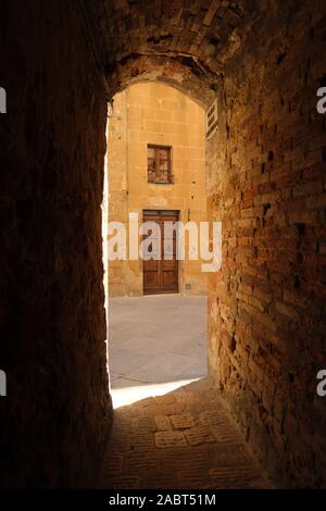 Eine schmale gewölbten Gasse in der Altstadt und die Architektur von der UNESCO zum Weltkulturerbe Pienza Renaissance der Stadt auf einem Hügel in der Toskana Italien Stockfoto