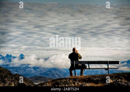 Europa, Süd West Grönland, Maniitsoq, Mann auf dem Sitz neben dem Friedhof Stockfoto