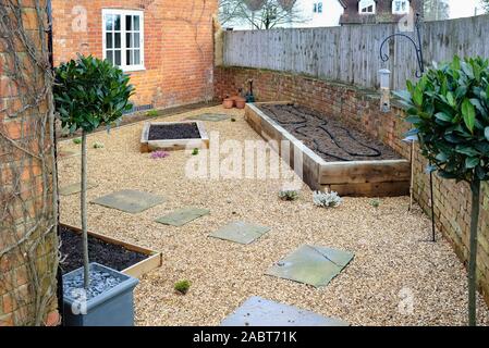Kleiner Garten Design mit harten Landschaftsgestaltung, Kies und York Stein weg, Eiche sleeper angehobenen Betten und Bay Bäume Stockfoto