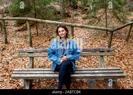 Junge Frau sitzt auf einer Bank im Wald, Haute Savoie, Französische Alpen. Stockfoto