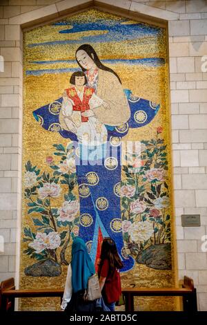 Besucher letzten eine Japanische Mosaik in der Verkündigung Römisch-katholische Basilika, Nazareth, Galiläa, Israel. Stockfoto