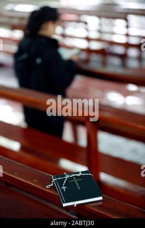 Frau zu beten und Bibel mit Rosenkranz auf eine Kirche Bank. Basilika Unserer Lieben Frau von La Vang. Pilgerfahrt. La Vang. Vietnam. Stockfoto