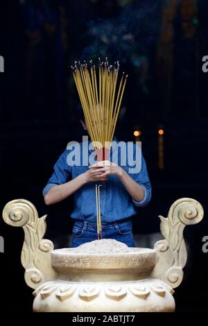 Ha Chuong Hoi Quan Pagode. Junge chinesische betende Frau mit großen Räucherstäbchen in der Hand. Ho Chi Minh City. Vietnam. Stockfoto