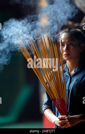 Ha Chuong Hoi Quan Pagode. Junge chinesische betende Frau mit großen Räucherstäbchen in der Hand. Ho Chi Minh City. Vietnam. Stockfoto