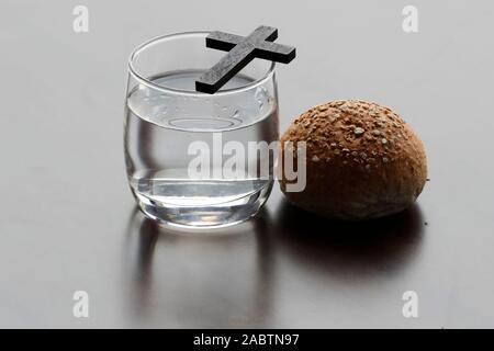 Christian Kreuz, Glas Wasser, und die Heilige Bibel während der Fastenzeit. Eine feierliche Religiosität, die am Aschermittwoch beginnt und endet mit dem Karsamstag. Stockfoto