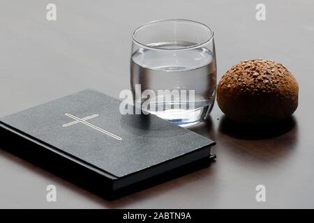 Brot, ein Glas Wasser und heilige Bibel während der Fastenzeit. Eine feierliche Religiosität, die am Aschermittwoch beginnt und endet mit dem Karsamstag. Stockfoto