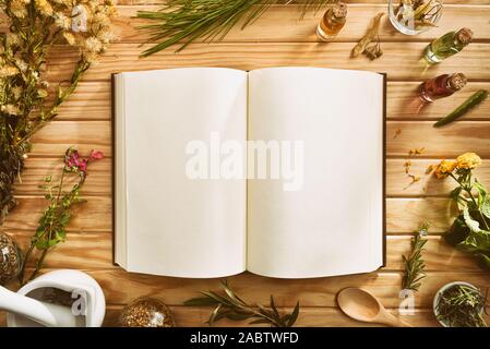 Leeres Buch Rezepte für die Zubereitung von natürlichen pflanzlichen Medizin auf Holztisch mit Medizinischen und Aromatischen Pflanzen. Ansicht von oben. Horizontale compositi Stockfoto