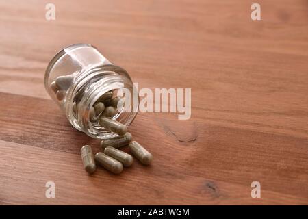 Glas Glas mit Medikation Kapseln auf Holz Tisch gefüllt. Erhöhte anzeigen. Horizontale Komposition. Stockfoto