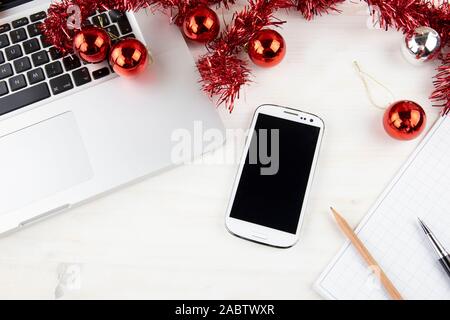 Computer Job an Weihnachten Konzept: Nahaufnahme, Ansicht von oben in einem Aluminium Laptop öffnen, Smartphone, Rot wreath Dekoration, rote und silberne Kugeln, p Stockfoto