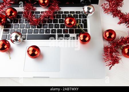 Computer Job an Weihnachten Konzept: Nahaufnahme in Low Angle View aus Aluminium Laptop öffnen, Rot wreath Dekoration und rote und silberne Kugeln auf Stockfoto