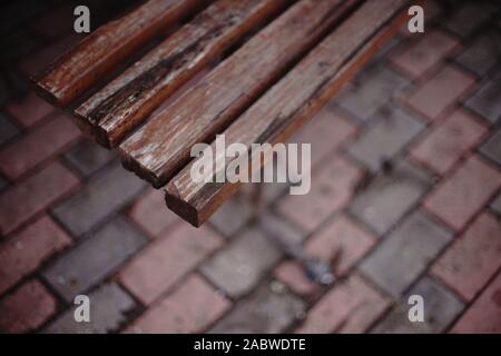 Alte Holzbank mit abblätternder Farbe, Ansicht von oben, verschwommenes Fliesenboden. Stockfoto
