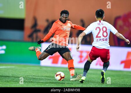 Senegalesischer Fußballspieler Makhete Diop von Peking Renhe F.C., links, hält den Ball in der 29. Runde der Chinese Football Association Super League (CSL) gegen Shanghai SIPG in Peking, China, 27. November 2019. Peking Renhe band das Spiel mit Shanghai SIPG mit 3-3. Stockfoto