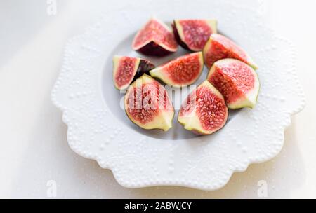 Reifen Feigen auf einem weißen Keramikplatte auf weißem Hintergrund gehackt Stockfoto