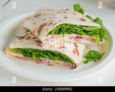 Italienische take away, traditionelle italienische Piadina mit Schinken und Salat. weißer Hintergrund Stockfoto