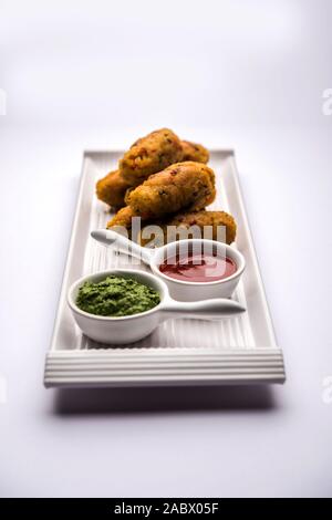 Gemüse Poha Schnitzel oder abgeflachte Reispasteten serviert mit Tomatenketchup und grünem Chutney Stockfoto