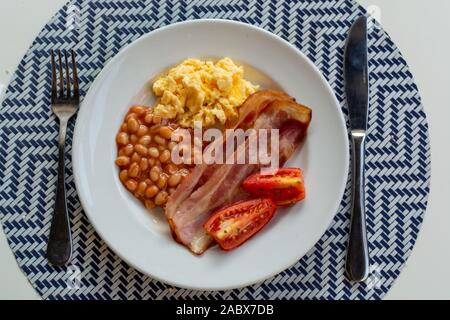 Englisches Frühstück mit gegrilltem Speck, Tomaten, Rührei und gebackene Bohnen in Tomatensoße in Spanien Stockfoto