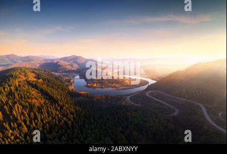 Antenne drone Blick über den Herbst in den Bergen mit Mountain Road Serpentine, Fluss und Wald. Landschaftsfotografie Stockfoto