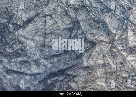 Dünnes Eis auf dem Teich, Textur Hintergrund Hintergrund Tapete. Eine ungleichmäßige grobe Schicht aus Eis mit gefrorenen Risse. Schnee im Winter kalte Eis frost texturierte Effe Stockfoto