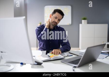 Foto von Unternehmer leiden unter Nackenschmerzen Stockfoto