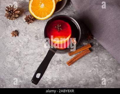 Alte Metall pan Pot an leckeren Glühwein mit Topf mit Gewürzen und Orange Früchte und Geschenkboxen auf hölzernen Tisch. Ansicht von oben. Stockfoto