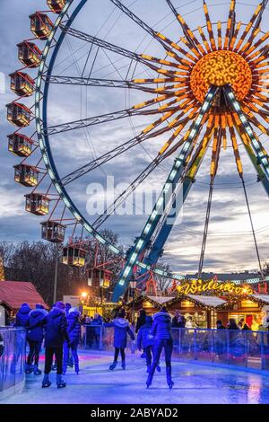 Skater Skate auf der Eisbahn vor dem Riesenrad am Berliner Weihnachtzeit Weihnachtsmarkt, Alexanderplatz, Mitte, Berlin Stockfoto