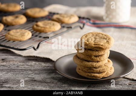 Frisch gebackene Erdnussbutter-Kekse mit einem eiskalten Glas Milch. Serviert Ono ein rustikaler Holztisch. Stockfoto