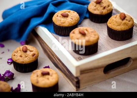Eine hölzerne Fach mit grundlegenden Muffins mit Mandel auf der Oberseite Stockfoto