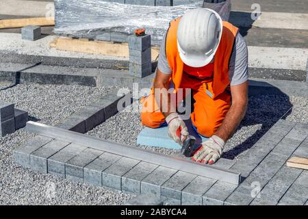 Builder Festlegung Pflasterklinker outdoor auf dem vorbereiteten Untergrund. Stockfoto