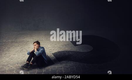 Verärgert und junge Teenager sitzen auf dem Boden verwirrt sie nachdenklich auf der Suche einen Schatten wirft in einem Interview mark umgewandelt. Schwierig decis Stockfoto