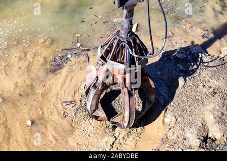 Kran Grabber in der Tätigkeit von Binnenschiff, Arbeiten am Fluss Verkleidung an der Baustelle. Stockfoto